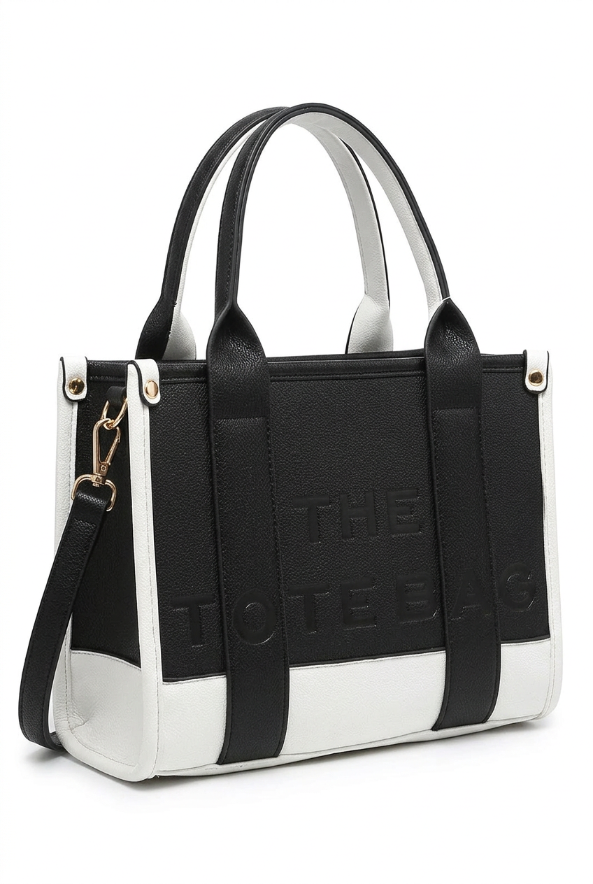 A black and white tote bag with embossed 'THE TOTE BAG' branding on the front, featuring dual top handles and a detachable shoulder strap, set against a plain white background.