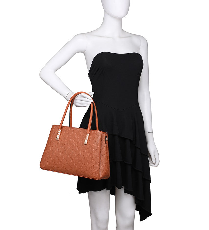 A white mannequin wearing a black strapless ruffled dress and holding a structured tan handbag with double top handles and gold-tone hardware, shown against a plain white background.