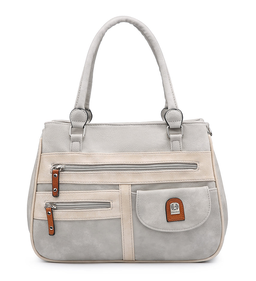 A structured handbag in light gray faux suede with beige trim panels, dual top handles, two front zip pockets, and a front flap pocket with a small brown leather brand patch.