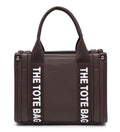A dark brown pebbled tote bag with dual top handles and bold white vertical text reading 'THE TOTE BAG' on both sides, shown against a plain white background.