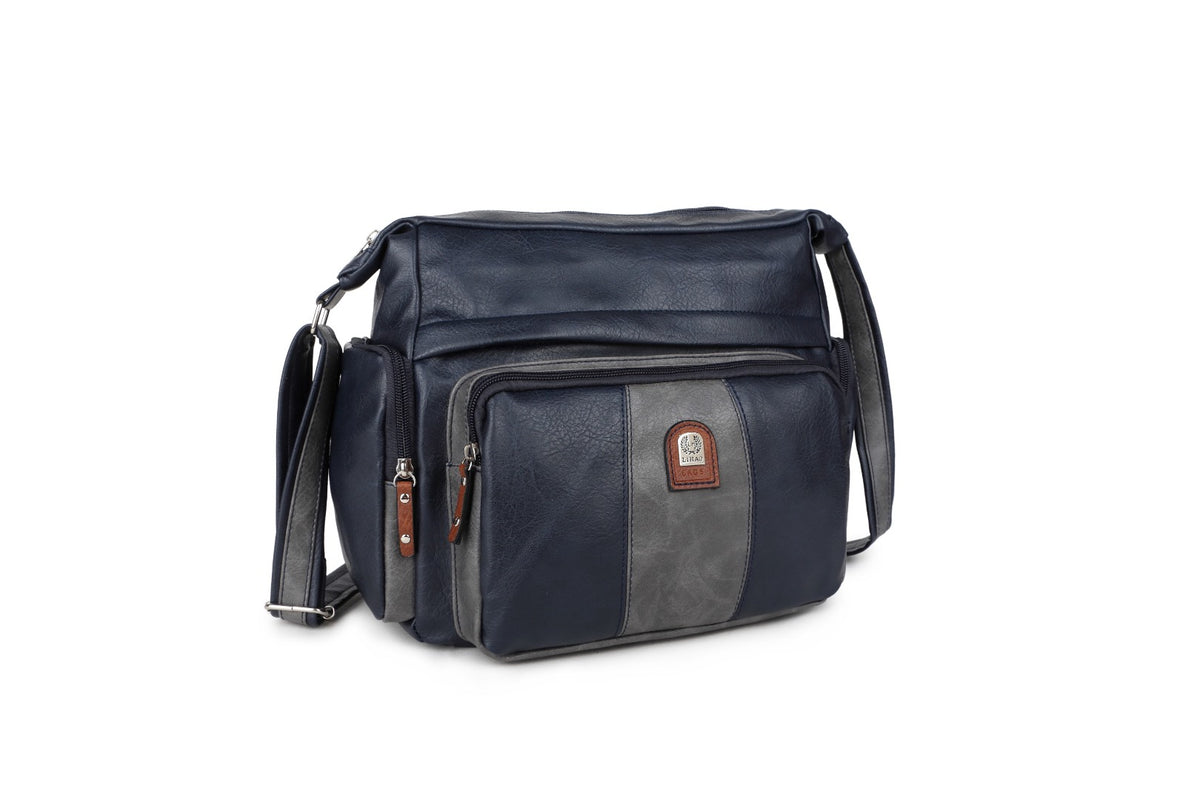 A navy blue faux leather crossbody bag with a front zippered pocket featuring a gray vertical panel and a small brown brand patch, shown on a white background.