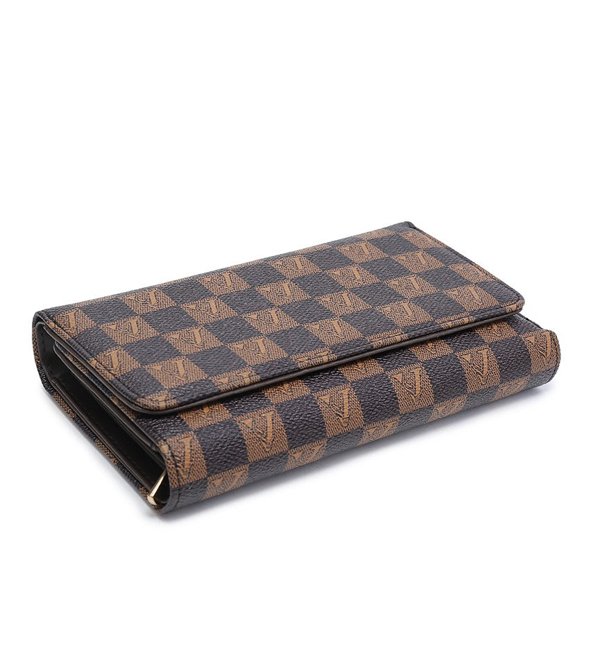 A ong wallet in the brand's classic Damier Ebene checkered pattern, featuring brown and black checkers with subtle gold V monogram details, shown on a plain white background.