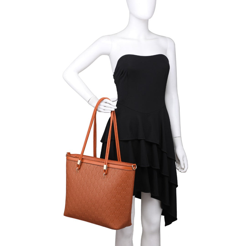 A brown textured tote bag with gold-tone hardware, held by a white mannequin wearing a black strapless dress against a plain white background.